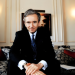A black and white portrait of Bernard Arnault, looking contemplative, overlaid with a subtle texture of a cashmere fabric.