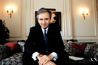 A black and white portrait of Bernard Arnault, looking contemplative, overlaid with a subtle texture of a cashmere fabric.